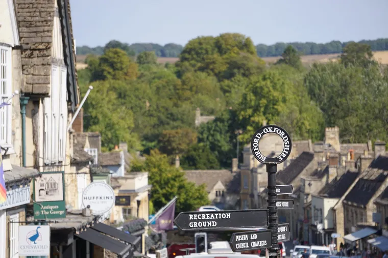 The cast-iron Burford signpost on the high street, with honey-stone rooftops falling away to the Windrush valley behind