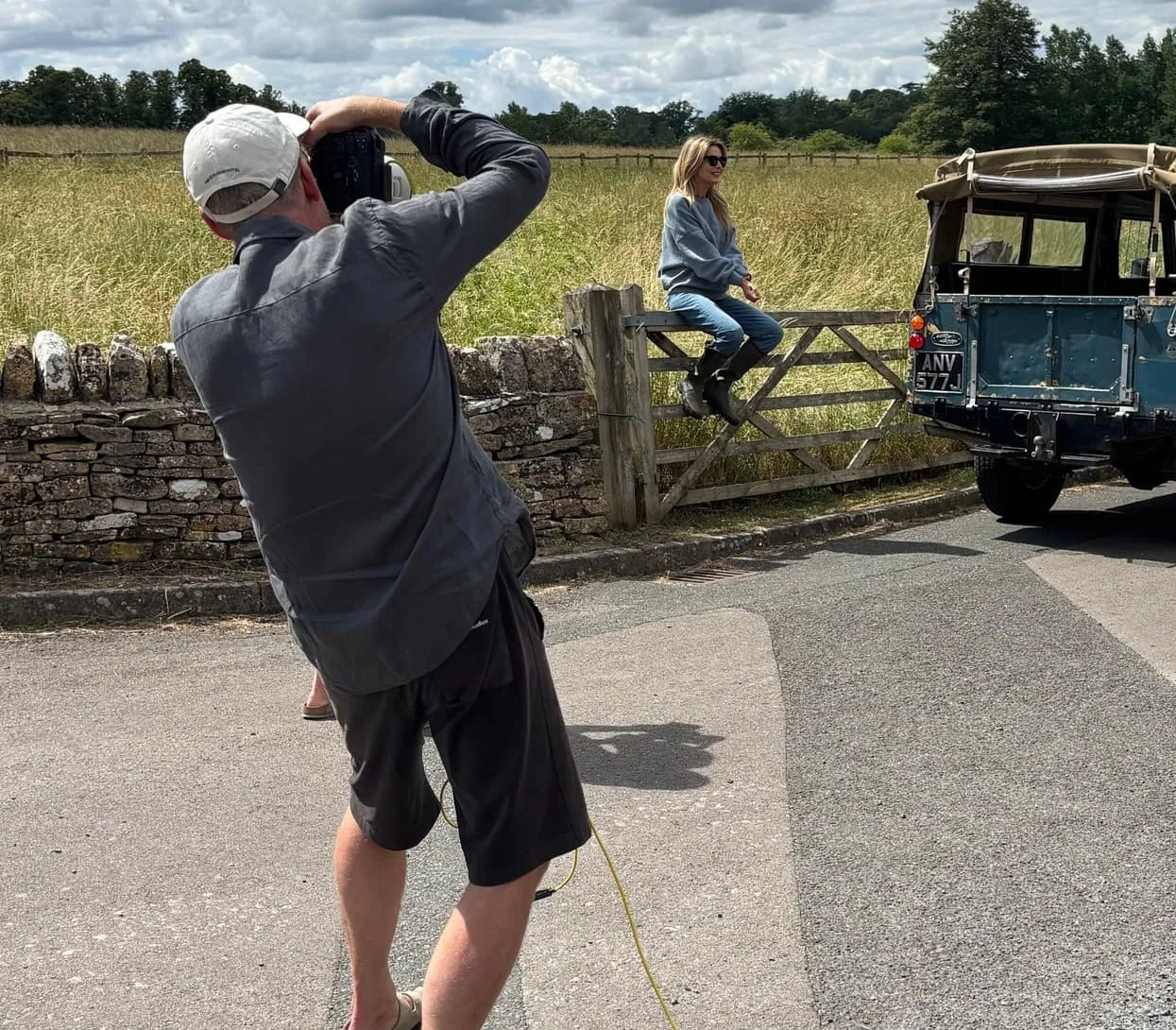 A photo shoot in a Northern Cotswolds lane, with a photographer at work, a model on a field gate and our 1971 Land Rover Series 2a