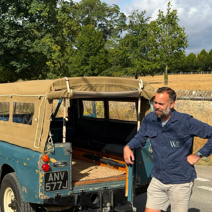 Phil beside our 1971 Land Rover Series 2a with her tailgate down, on a lane beside a summer field